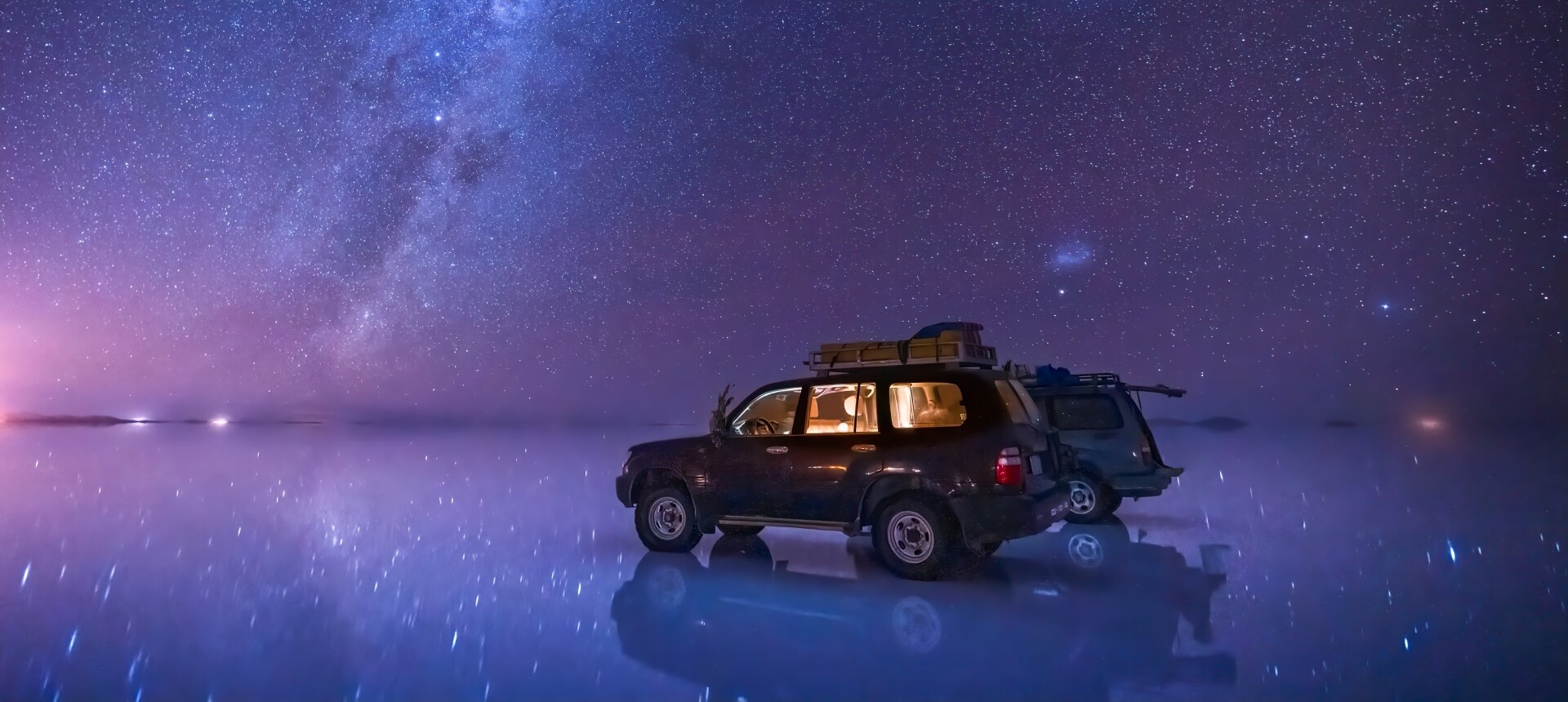 ボリビア、鏡張りのウユニ塩湖と星空に佇む自動車