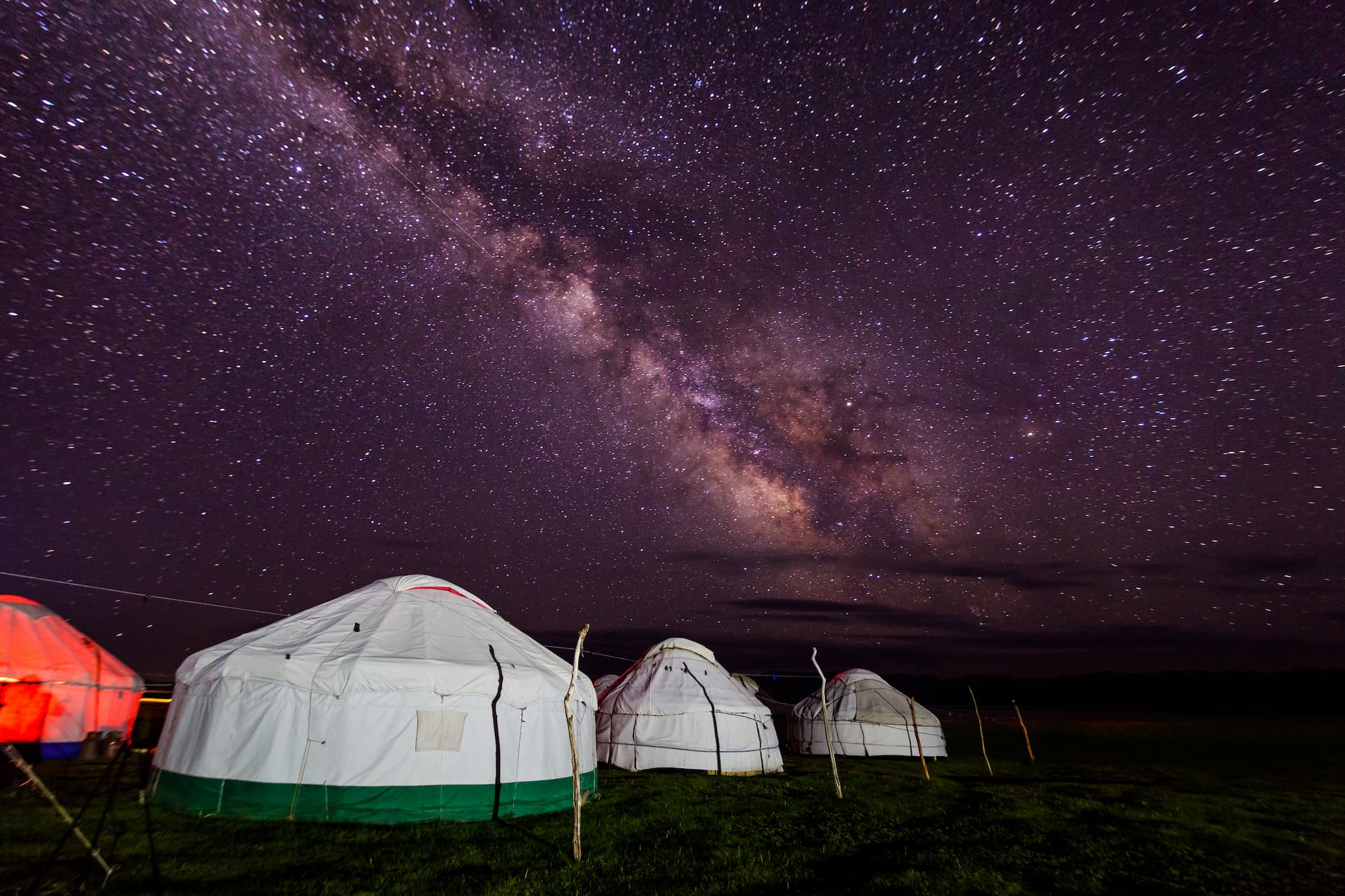 Group of yurts against the starry sky at night in the desert.