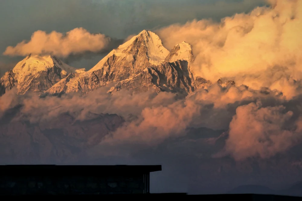 Kavya Himalayasから望む夕景のヒマラヤ。雲の上に雪をかぶった峰々が並ぶ